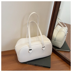 Detail of white lychee leather handbag with silver hardware on a dark wood table