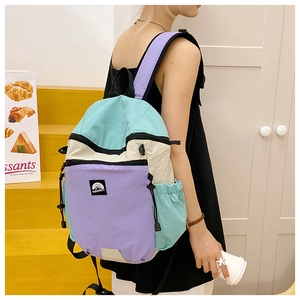 Detail view of multicolored patchwork nylon backpack with light blue and beige panels