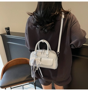 Detail of light gray glossy Boston bag with pearl lace charms and dual front pockets