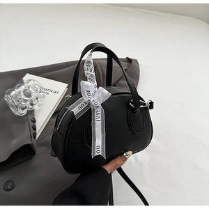 Black half-moon bowling bag featuring lychee grain texture and a decorative white ribbon