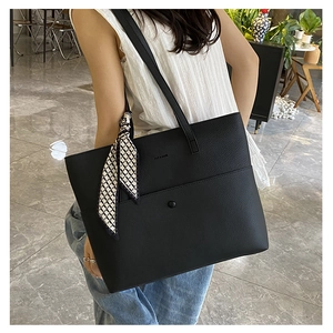 Detail of black pebbled leather tote bag with silk scarf and Daily & Bags logo lettering