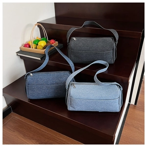 Three minimalist denim shoulder bags in blue and grey displayed on wooden stairs