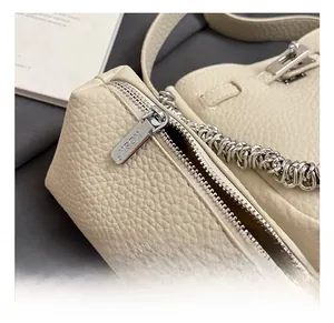 Dettaglio della borsa a secchiello in pelle beige martellata con catena d'argento e zip KOSK