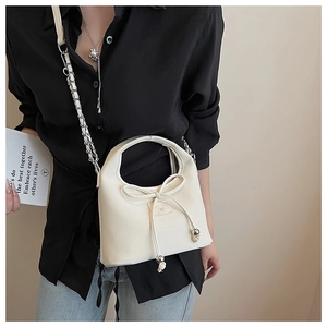 Détail d'un sac dumpling beige avec cordon de serrage, nœud 3D et chaîne métal