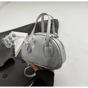 Detail of silver metallic leather handbag with lychee texture and ribbon bow on grey suit