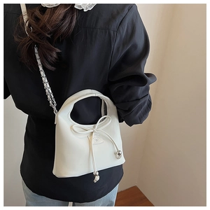 Vue détaillée du sac bandoulière crème avec nœud décoratif et perles métalliques