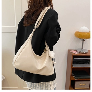 Detail of cream large tote bag with plush bear charm on a minimalist shoulder strap