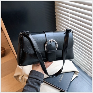 Detail of black glossy faux leather shoulder bag with bold silver metal buckle accent