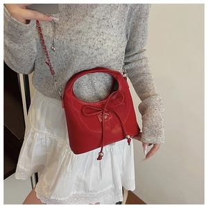 Selfie miroir montrant un sac à bandoulière rouge brillant avec nœud et chaîne