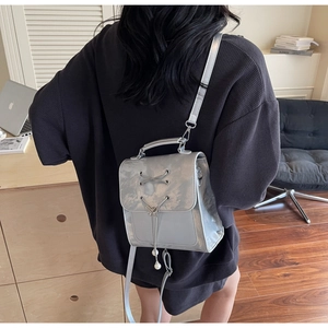 Détail d'un mini sac à dos argenté métallisé avec cordon de serrage et pendentif perle