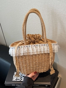 Rustic straw handbag with white lace trim and drawstring liner on a vintage book