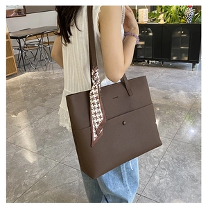 Detail of dark brown litchi pattern leather tote bag with houndstooth silk scarf accessory