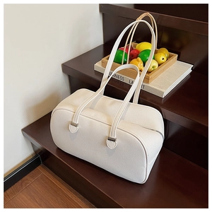 White litchi grain boston bag with long handles placed on a dark wooden stairs