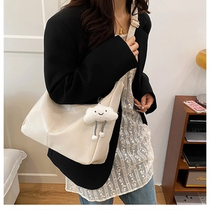 Detail of minimalist cream tote bag featuring a cute plush cloud charm and golden buckle