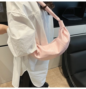Detail view of light pink patent leather crescent bag featuring iconic knotted shoulder strap