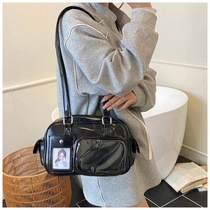 Detail of black patent leather bag featuring a clear photo slot and multi-pocket design