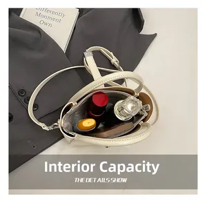 Top-down view showing interior capacity of minimalist beige bucket bag with cosmetics