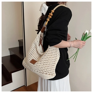 Détail du sac tressé crème avec bandoulière en perles de bois et écusson en cuir