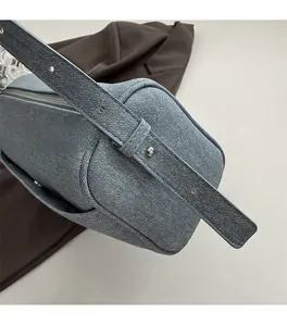 Detailed close-up of blue denim texture shoulder bag with silver metal hardware and strap
