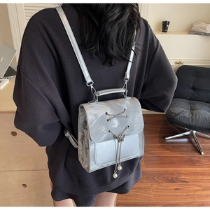 Détails du sac à dos argenté métallisé avec boucle papillon et breloque perle