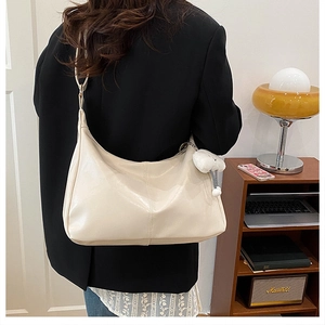 Detail view of cream tote bag with chic stitching and a plush cloud charm accessory