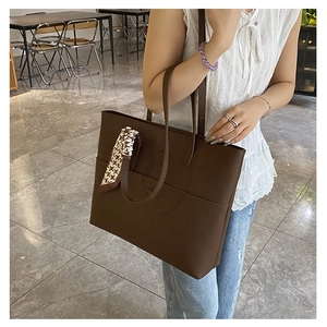 Detail of dark brown tote bag with lychee texture and houndstooth scarf on the handle