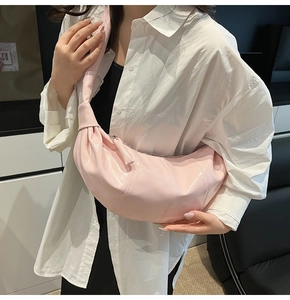 Detail of soft pink croissant bag showing shiny patent leather texture and pleated design