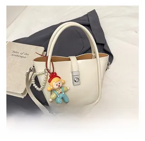Detail of white bucket bag with pearl strap, cartoon pendant and silver twist lock