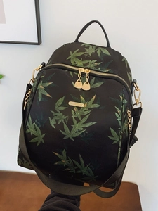 Black backpack featuring green bamboo leaf print with elegant gold hardware accents
