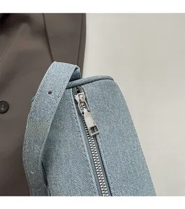 Close-up of smooth silver zipper and blue denim texture on trendy shoulder bag