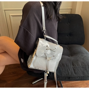 Close-up of metallic silver backpack featuring butterfly metal lock and pearl tassels