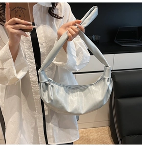 Metallic light blue crescent bag featuring a knotted shoulder strap and soft leather folds
