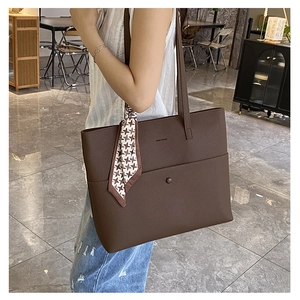 Brown tote bag with lychee texture and houndstooth scarf worn by a model in an office