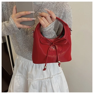 Gros plan d'un sac à main en cuir verni rouge avec un nœud et des détails en perles