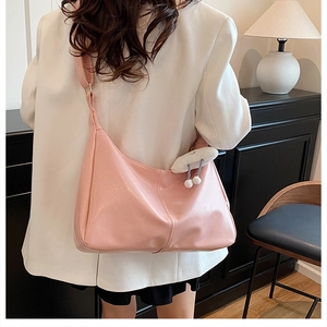 Pink glossy hobo bag with white cloud plush charm shown in a cozy home setting