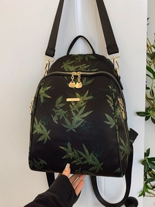 Fashionable black backpack with green bamboo leaf prints and gold metal zippers