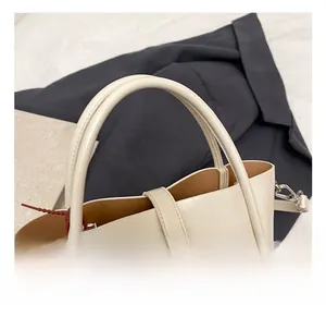 Close-up of cream leather bucket bag showing silver twist lock and pearl doll charm
