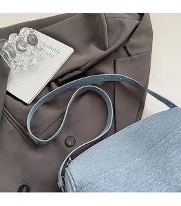 Detail of light blue denim texture crossbody bag with sleek strap on aesthetic background