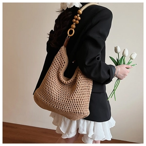 Détail du sac seau en tricot avec bandoulière en perles de bois et motif ajouré