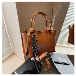 Vue détaillée du sac seau en cuir marron caramel avec pompon tressé et anses rondes