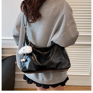 Detail of black large-capacity hobo bag with quilted texture and plush cloud pendant