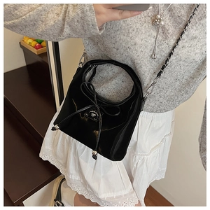 Détail du sac bandoulière noir verni avec plaque argentée et cordon à nœud élégant