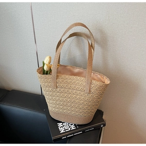 Dettaglio dell'intreccio traforato di una borsa tote in paglia beige con fodera