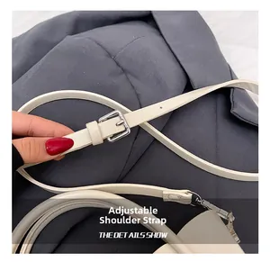Detail of adjustable cream leather shoulder strap with silver buckle for crossbody bag