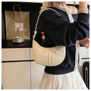 Close-up of off-white crescent underarm bag featuring lychee texture and rivet pockets
