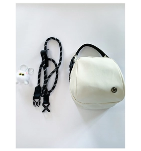 Detail of cream shell bag with woven strap and cute white cat plush charm