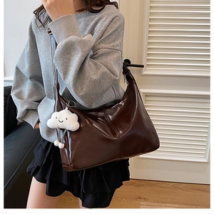 Macro detail of the dark brown glossy leather texture and cute cloud charm on tote bag