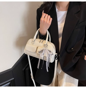 Detail of cream Boston bag featuring lace bow pendant and pearl strap charms