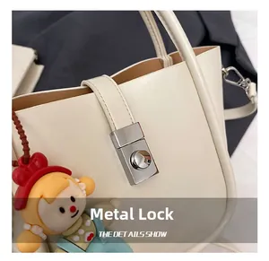 Detail shot of the cream-colored handbag's silver metal clasp and fine leather texture