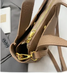 Close-up of smooth gold metal zipper and litchi grain texture on brown leather tote bag